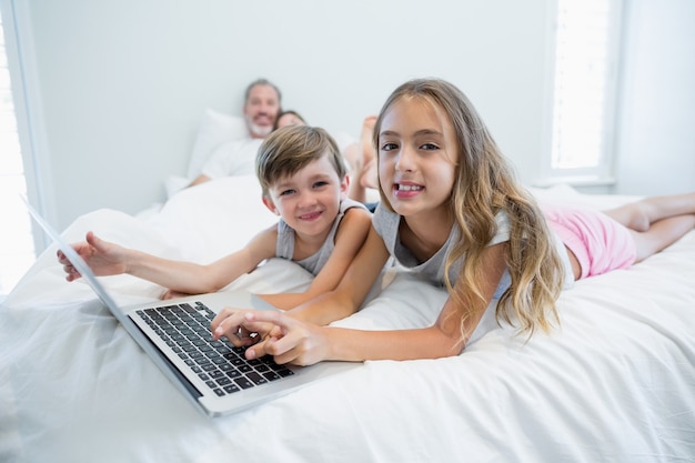 Glimlachend meisje en jongen met laptop op bed in de slaapkamer thuis