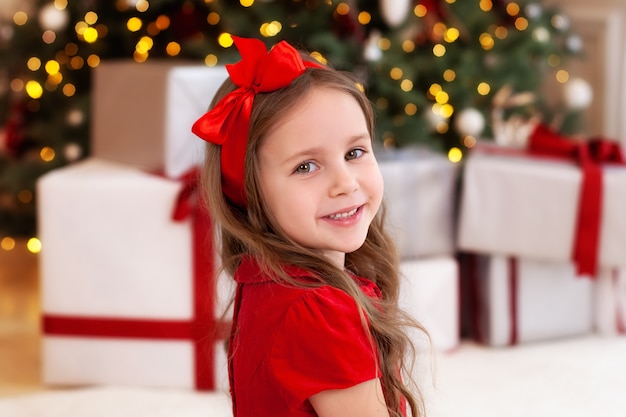 Glimlachend meisje in de buurt van de kerstboom met cadeautjes