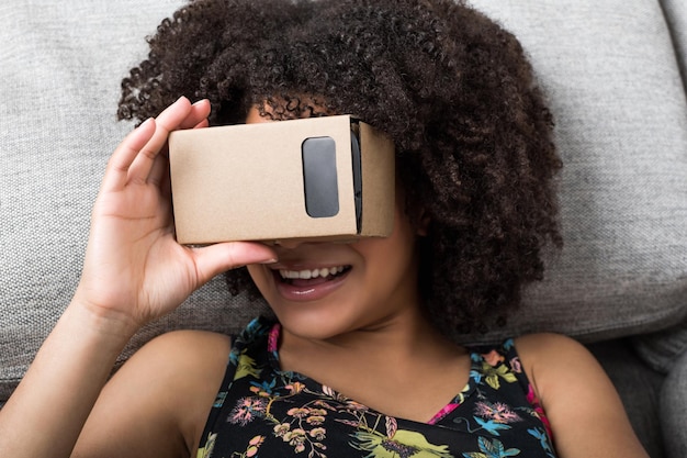 Glimlachend meisje met behulp van virtual reality-apparaat kartonnen vr op de bank