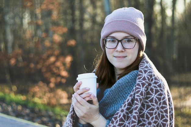 Glimlachend meisje met een bril met een kopje warme koffie in een kopje