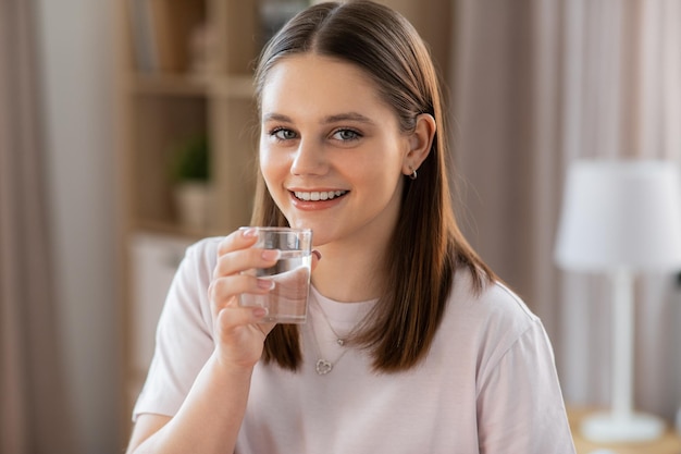 glimlachend meisje met een glas drinkwater thuis
