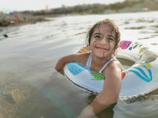 Glimlachend meisje met opblaasbare ring in het meer