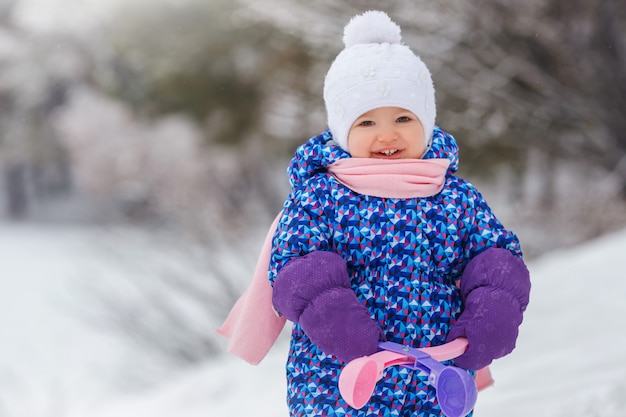 Glimlachend meisje met plezier in het winterpark Concept van warme kleding bij koud winterweer