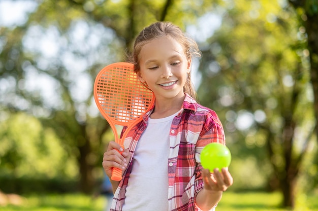 Glimlachend meisje met tennisracket en bal