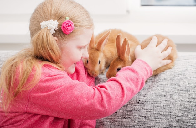 Glimlachend meisje met twee konijnen binnen