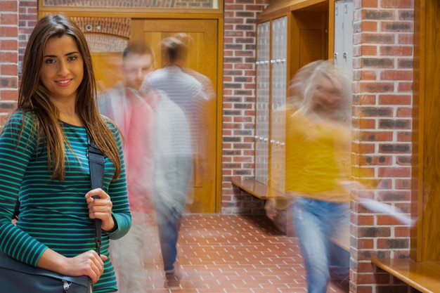 Glimlachend meisje met vage studenten die gang lopen