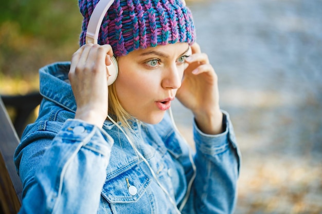 Glimlachend meisje ontspannende muziek een smartphone en koptelefoon Buiten portret van een trendy meisje herfst melodie concept val gezellige sfeer vrouw met grote headphon