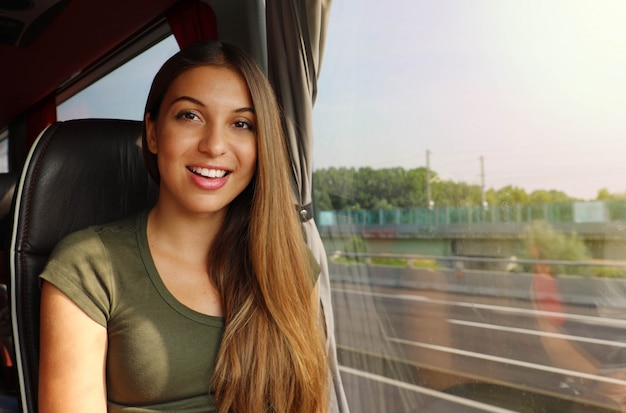 Glimlachend meisje reist in de bus met de weg uit het raam kijkend naar de kwam