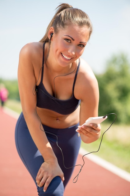 Glimlachend meisje rust na het joggen en muziek luisteren op koptelefoon. Camera kijken.