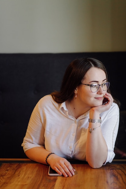 Glimlachend meisje tijd doorbrengen in een straatcafé met behulp van digitale gadget