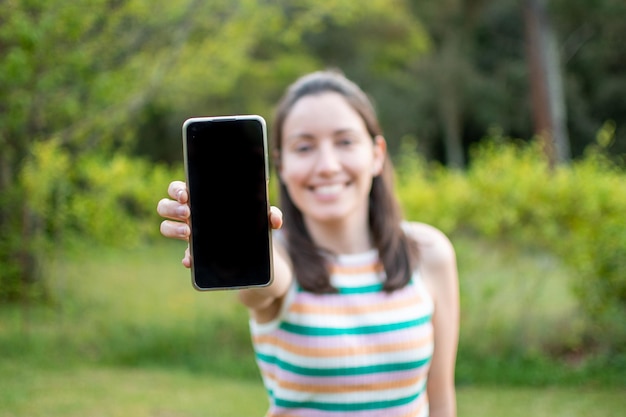 Glimlachend meisje toont het mobiele scherm op een zomerdag Gevoel van geluk