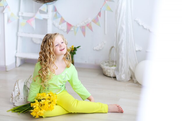 Glimlachend meisje van schoolleeftijd met gele bloemen in haar handen