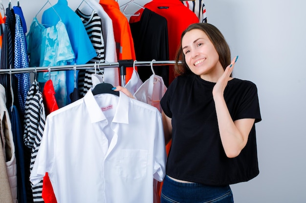 Glimlachend meisje voelt zich gelukkig door shirt op kledingachtergrond te houden