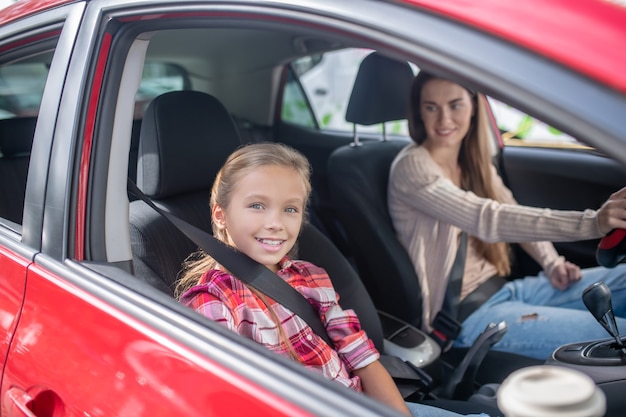 Glimlachend meisje zit met passagiersstoel, rijden met haar moeder