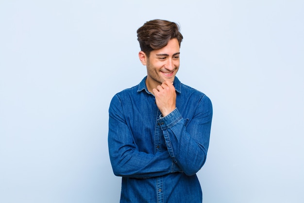 glimlachend met een vrolijke, zelfverzekerde uitdrukking met de hand op de kin, benieuwd en naar de zijkant kijkend