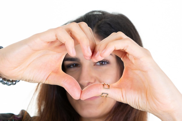 Glimlachend mooi meisje maken hart vorm voorgezicht oog met haar vingers hand geïsoleerd op een witte achtergrond