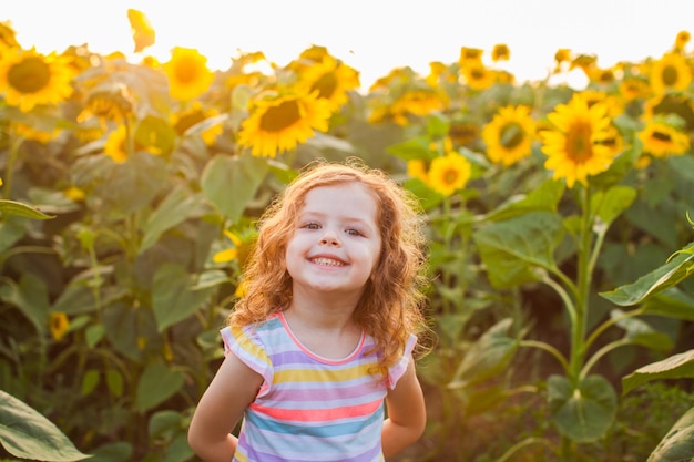Glimlachend mooi meisje op zonnebloemen veld achtergrond. Fijne zomervakantie.