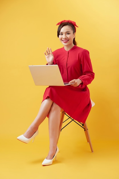 Glimlachend mooi vrouwenportret met laptop op gele achtergrond