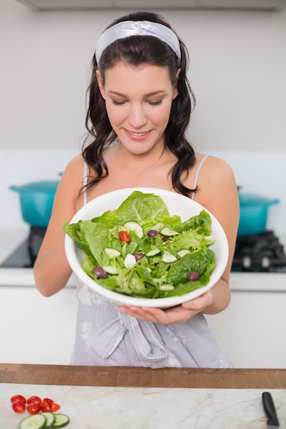 Glimlachend mooie brunette die gezonde salade toont