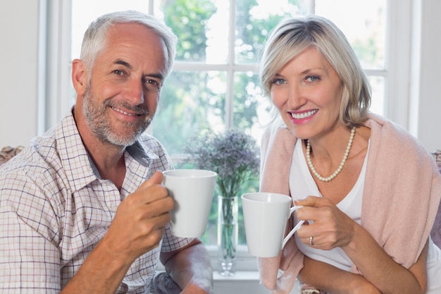 Glimlachend ouder paar met koffiekoppen thuis