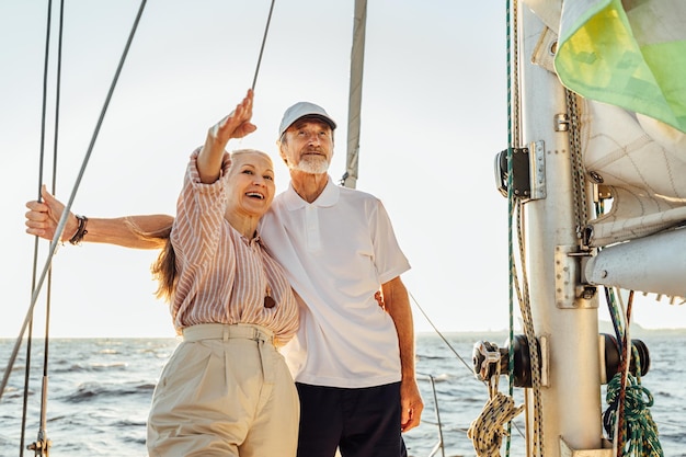 Glimlachend oudere echtpaar omhelst elkaar in een zeilboot tegen de lucht