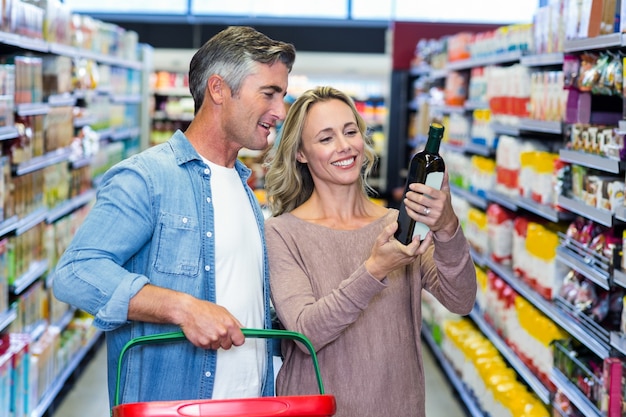 Glimlachend paar dat fles wijn bekijkt