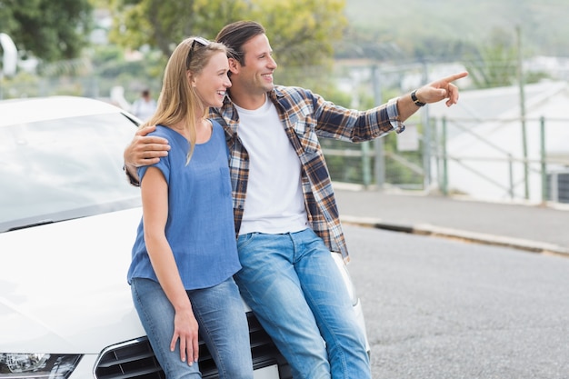 Glimlachend paar dat op de bonnet leunt