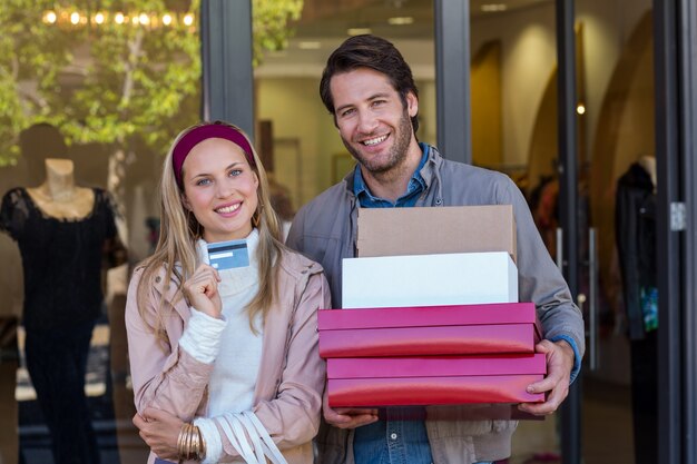 Glimlachend paar die creditcard tonen en dozen dragen