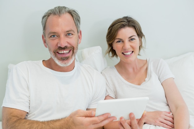 Glimlachend paar met behulp van digitale tablet op bed in de slaapkamer thuis