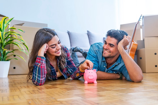 Glimlachend paar met piggybank in nieuw huis