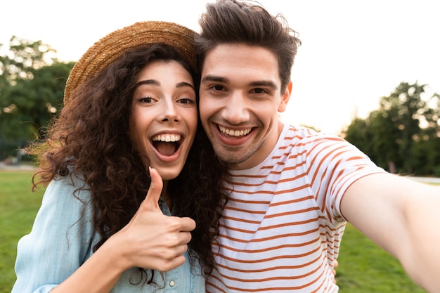 glimlachend paar wandelen in groen park, en het nemen van selfie op smartphone