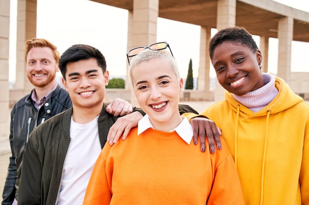 Glimlachend portret van een vrolijke groep jongeren van verschillende rassen samen in de open lucht naar de camera kijken
