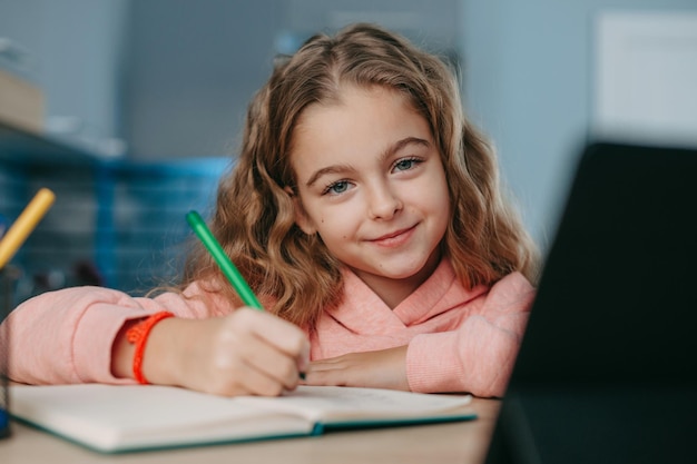 Glimlachend schoolmeisje dat tablet gebruikt om te studeren praten bij webcam online onderwijs coronavirus school d