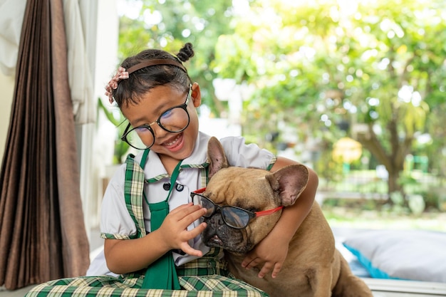 Glimlachend schoolmeisje dat thuis met haar Franse bulldog speelt