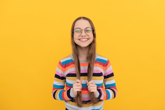 Glimlachend schoolmeisje nerd kind in bril voor visie heeft lang gezond haar haarverzorging