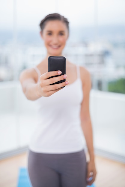 Glimlachend sportief brunette die haar telefoon houden