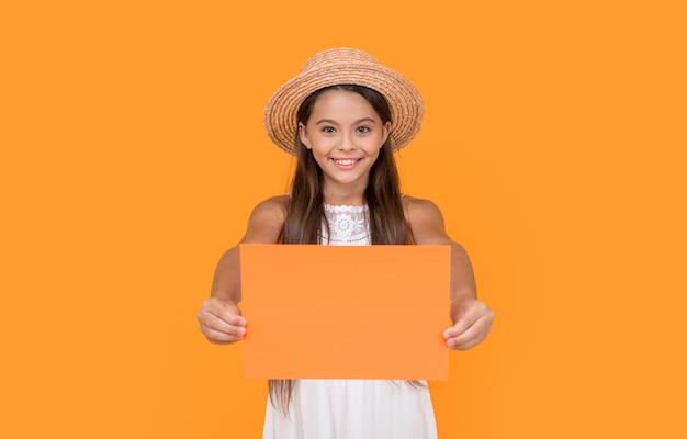 Glimlachend tienerkind met kopieerruimte op oranje papier op gele achtergrond