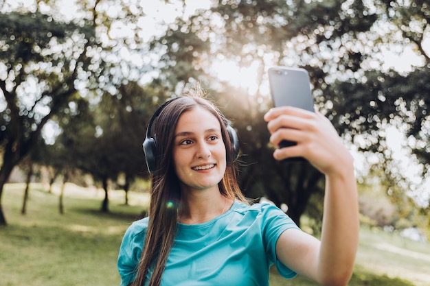 Glimlachend tienermeisje dat een selfie maakt met haar mobiel in de natuurlijke ruimte