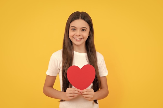 Glimlachend tienermeisje met valentijnshart op gele achtergrond valentijnsverkoop