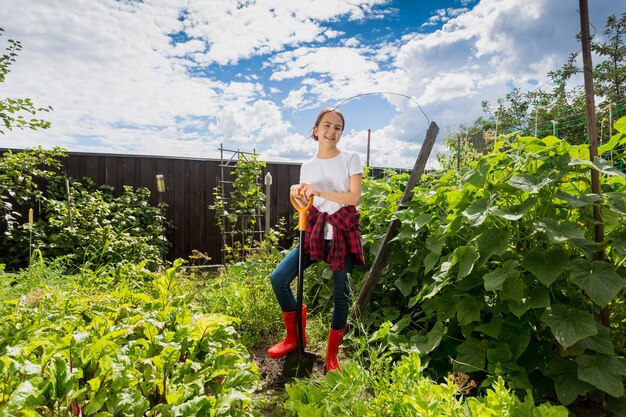 Glimlachend tienermeisje werken met schop in boomgaard