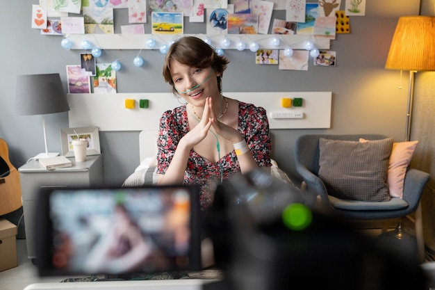 Foto glimlachend tienermeisje zittend op bed voor videocamera