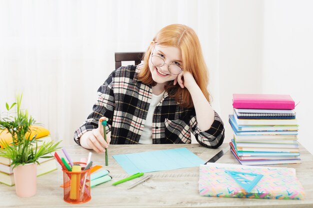 Glimlachend tienerstudent meisje in glazen huiswerk thuis onderwijs en school concept