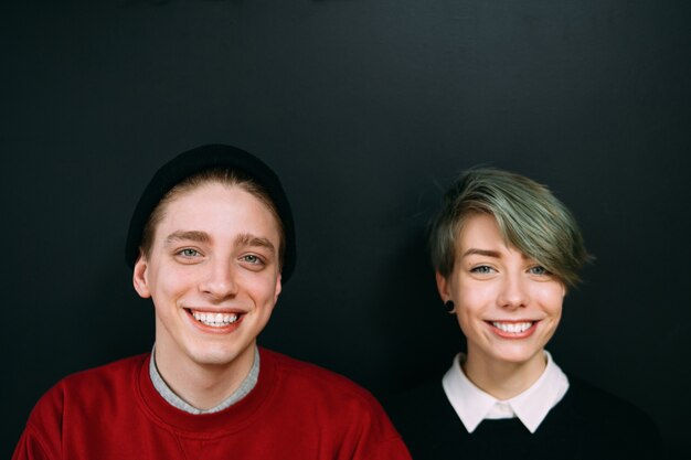 Foto glimlachend vriendenportret. bff vriendschap vrije tijd concept. tiener jonge hipster man en vrouw op donkere achtergrond