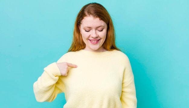 Glimlachend vrolijk en nonchalant naar beneden kijkend en wijzend naar de borst