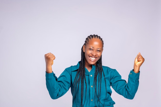 Glimlachend vrolijke jonge zwarte Nigeriaanse brunette vrouw meisje in poseren geïsoleerd op een witte achtergrond studio portret. Mensen oprechte emoties levensstijl concept. Bespotten kopie ruimte. Gebalde vuisten.