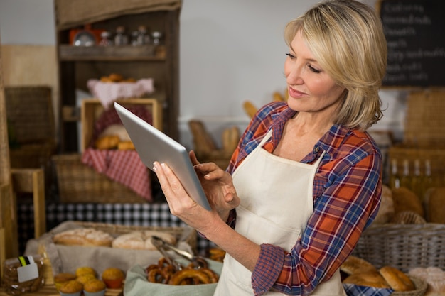 Glimlachend vrouwelijk personeel met behulp van digitale tablet aan balie