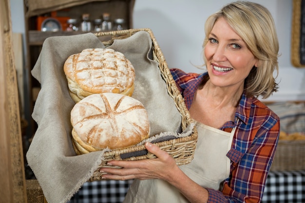 Glimlachend vrouwelijk personeel met rieten mand met brood aan balie