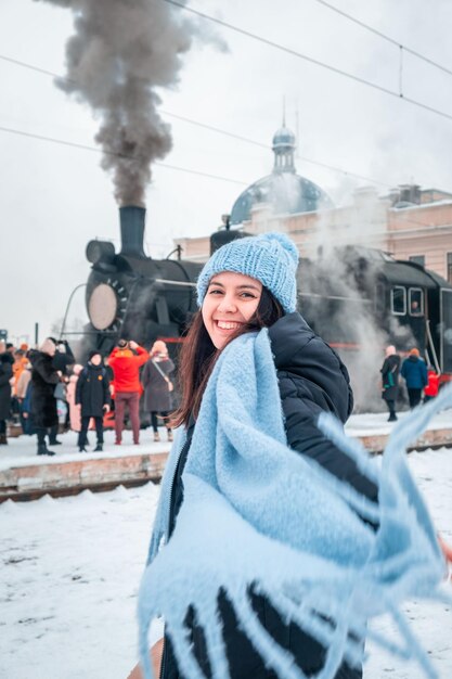 Glimlachend vrouwenportret op treinstation in de buurt van oude retro stoomtrein wintertijd