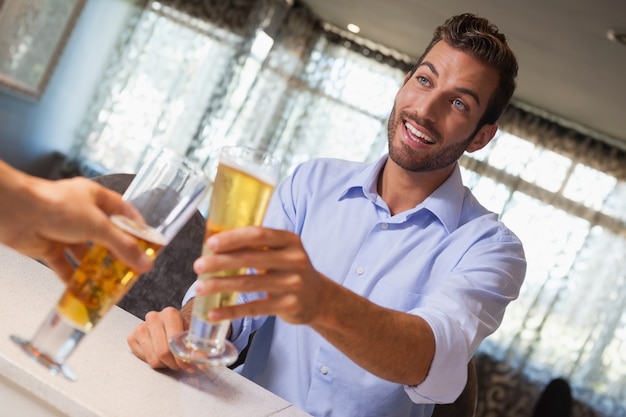 Glimlachend zakenman rammelende glas bier met barman