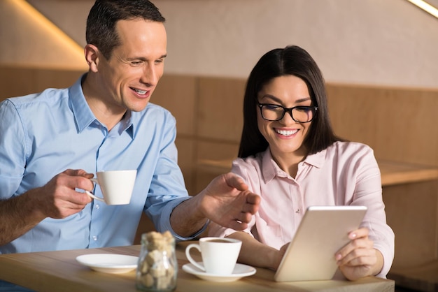 Glimlachend zakenpaar dat koffie drinkt in café en digitale tablet gebruikt